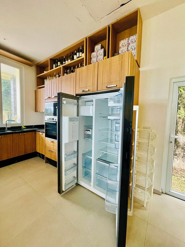 Una cocina con armarios de madera, un refrigerador y una ventana.