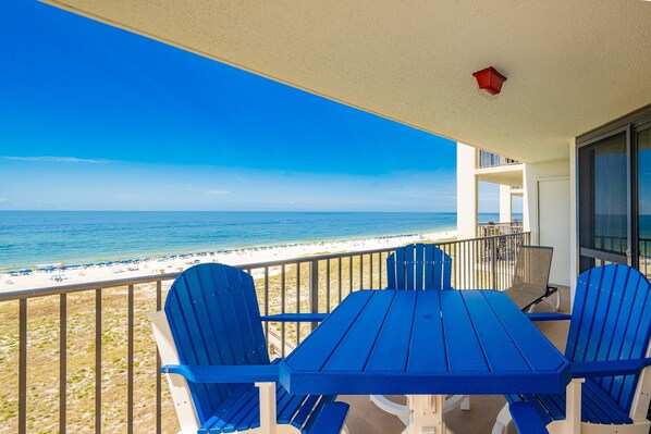 Un balcón con mesa y sillas con vista a la playa.