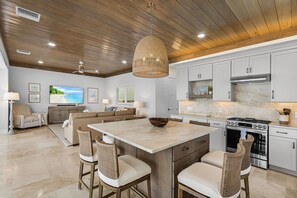 A modern kitchen with a large island, white cabinetry, and a built-in oven.