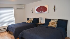 A bedroom with two beds, a painting on the wall, and a bedside table with a lamp.