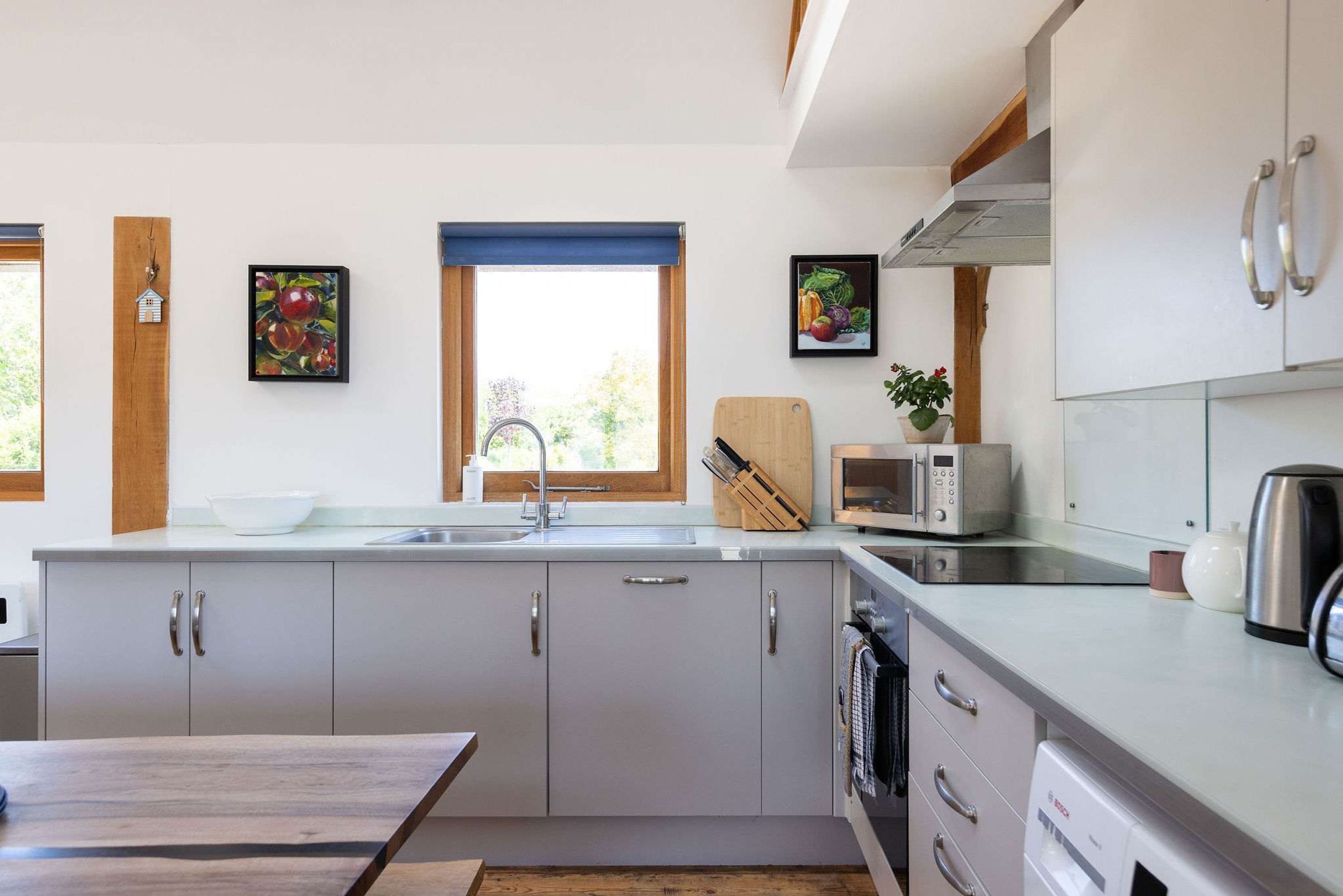 A modern kitchen with a sink, a microwave, a kettle, and a Bosch dishwasher.