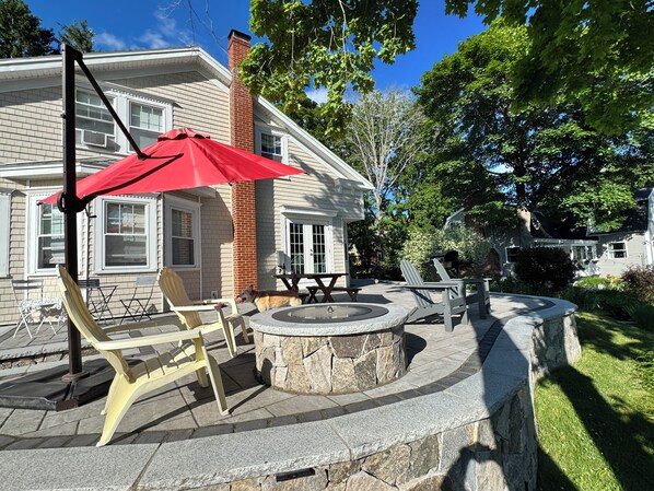 A patio with outdoor furniture, a fire pit, and a red umbrella. - Bright 3BR House • New patio, Fire Pit, Outdoor Shower, EV Charger • Beach 4min (York)