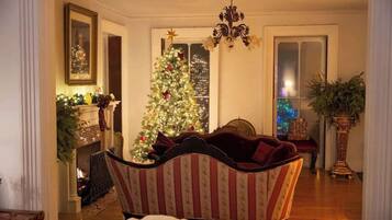 Un saló acollidor amb una llar de foc, un arbre de Nadal i un sofà estampat.