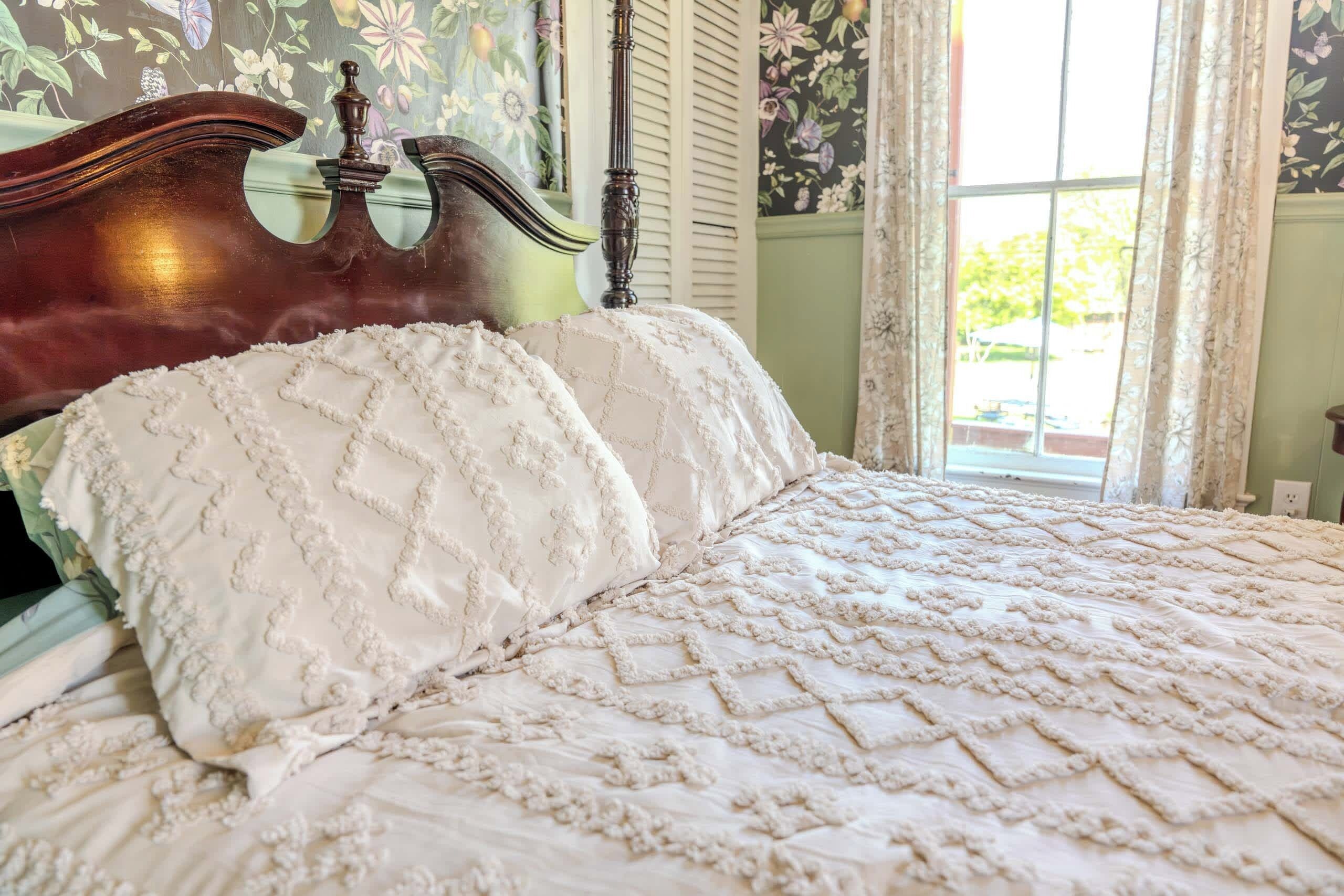 A bed with a quilted cover and a headboard with a mirror.