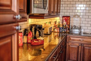 A kitchen with wooden cabinets, a coffee maker, and various condiments on the counter. - The Gould Residence & The Knapp Retreat (Seneca Falls)