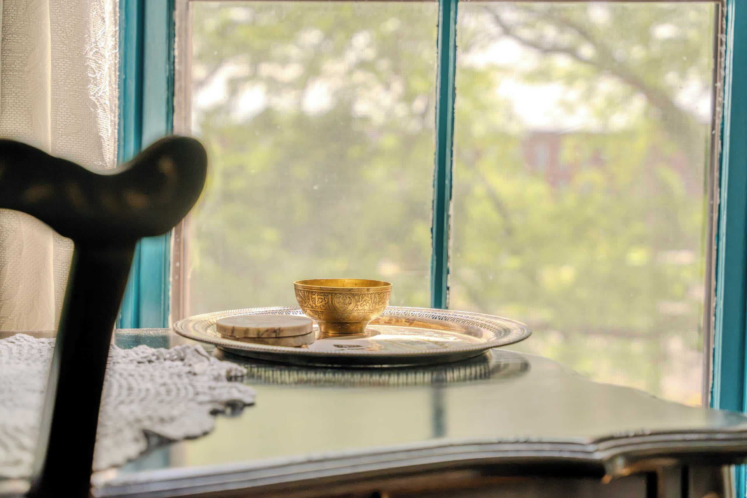 A table with a bowl and a plate, a chair, and a window with a view of trees.