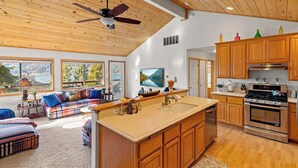 Une cuisine spacieuse avec des meubles de rangement en bois, un grand îlot central et un ventilateur de plafond.