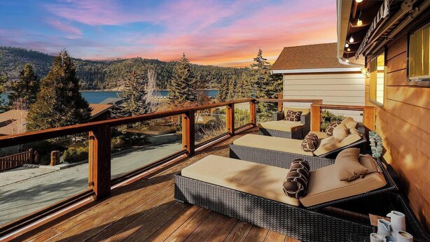 Une terrasse en bois, meublée de meubles en osier, avec vue sur un lac et une forêt.