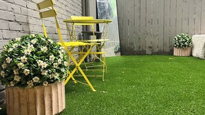 Takapihalla on keinonurmi, keltainen kokoontaitettava pöytä ja tuoli.