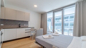 Habitación de hotel moderna con una cama, un escritorio y vistas de la ciudad a través de amplios ventanales.