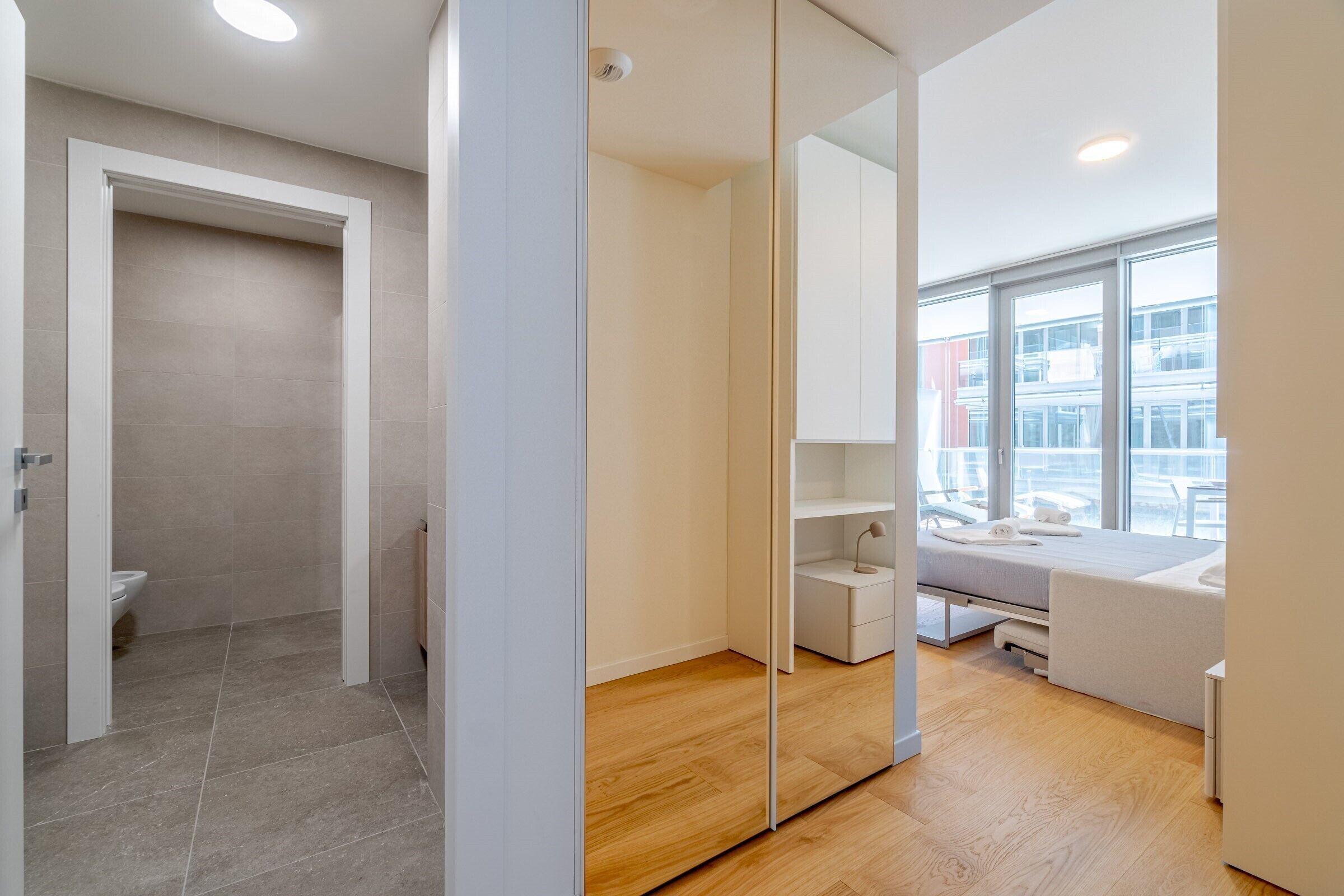Un baño moderno con ducha, inodoro y un espejo grande.