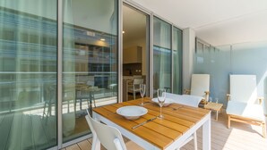 Un comedor moderno con una mesa de madera, sillas blancas y un separador de vidrio.
