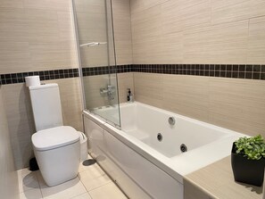 Un baño moderno con bañera, inodoro y cabina de ducha de vidrio.