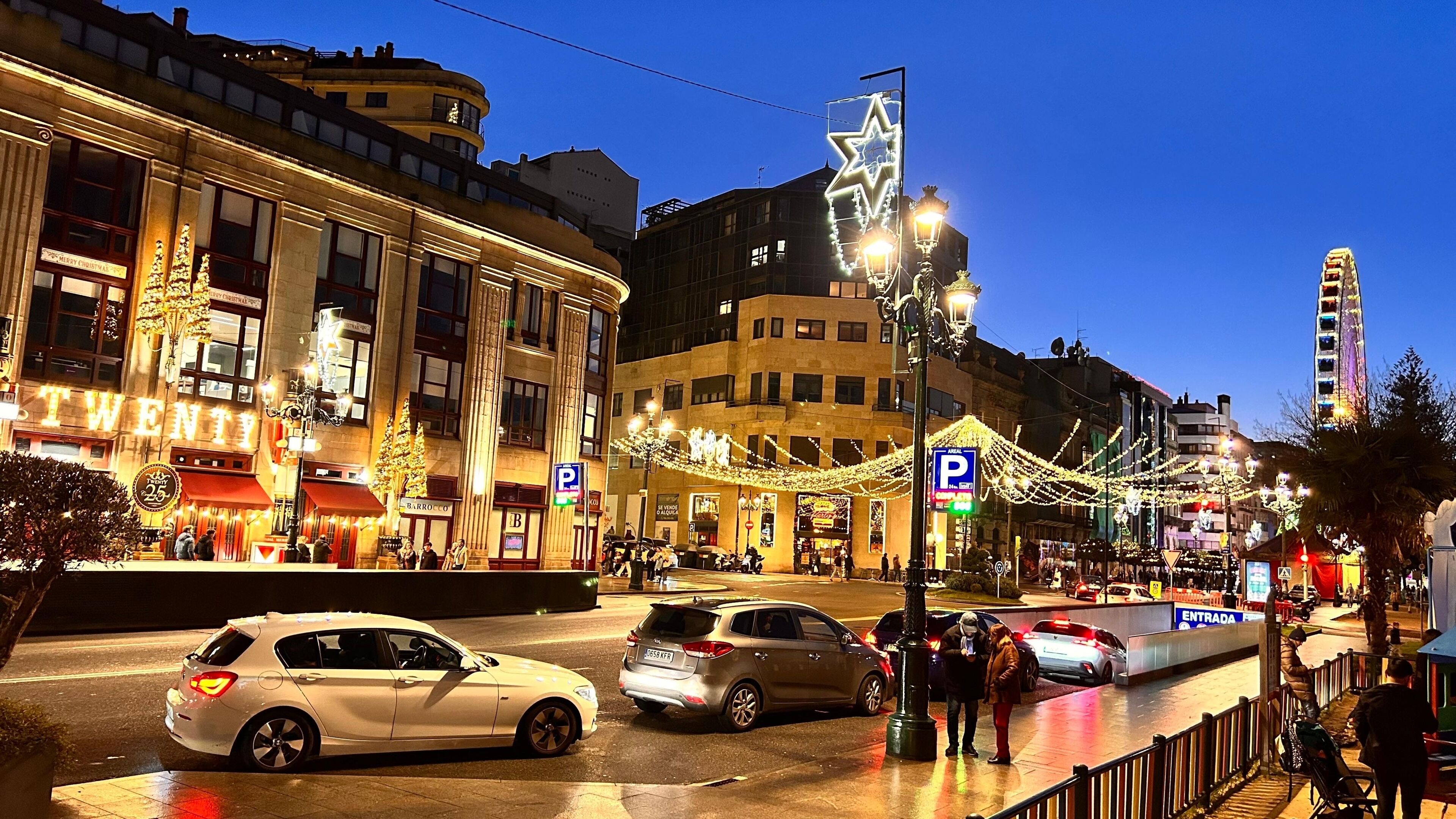 Une scène de rue avec des bâtiments illuminés, un grand panneau indiquant le chiffre « VINGT », et une grande roue en arrière-plan.