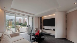 A modern living room with a large flat-screen TV, a sofa, a coffee table, and a balcony with a glass door. - lEPl Modern Apt, AC, Nice View, Balcony, Provenza (Medellín)