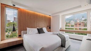 A modern bedroom with a large bed, a view of the city, and a wooden accent wall. - lEPl Modern Apt, AC, Nice View, Balcony, Provenza (Medellín)