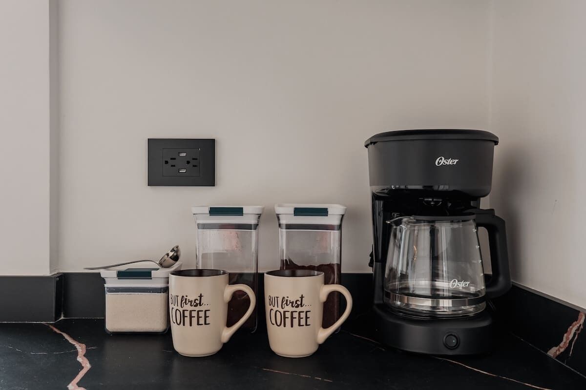 Un comptoir de cuisine avec une machine à café, deux tasses à café et deux récipients à café.