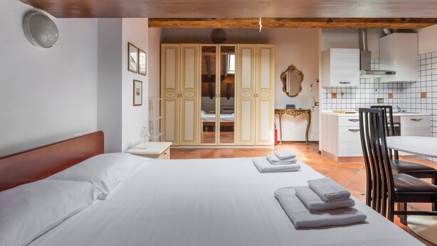 A bedroom with a large bed, a desk, and a wardrobe.