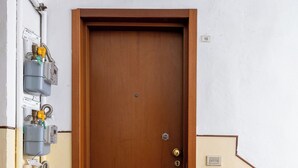 A wooden door with a brass doorknob, flanked by a tiled floor and a white wall.