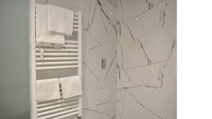 A bathroom with a white towel rack, a marble wall, and a light switch. - COZY NEW LOFT-CITYLIFE (Milano)