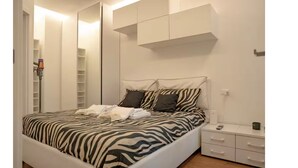 A bedroom with a zebra-patterned bedspread, a bedside table with a lamp, and a wardrobe with a mirror. - COZY NEW LOFT-CITYLIFE (Milano)