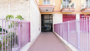 A narrow alleyway with a pink fence on both sides, leading to a building with a closed red shutter. - Roomy Family Apartment by Wonderful Italy (Bari)