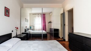 A bedroom with a bed, bedside tables, a dresser, a mirror, and a wardrobe. - Roomy Family Apartment by Wonderful Italy (Bari)