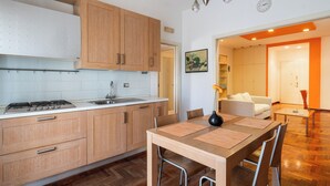 A modern kitchen with wooden cabinets, a gas stove, and a dining area with a table and chairs. - Roomy Family Apartment by Wonderful Italy (Bari)