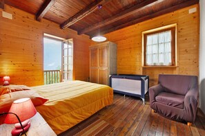 Une chambre dans une cabane en bois, avec un lit, une chaise, une fenêtre et une baignoire.