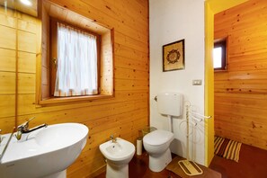A wooden-paneled bathroom with a sink, bidet, toilet, and a window with curtains. - La Vieille Ecole Holiday Home – Historic Schoolhouse Retreat in Montjovet (Montjovet)