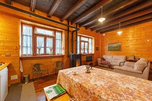 A cozy wooden cabin with a dining table, chairs, a sofa, and a fireplace. - La Vieille Ecole Holiday Home – Historic Schoolhouse Retreat in Montjovet (Montjovet)