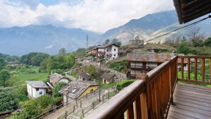 Un pueblo montañoso con casas tradicionales, un balcón de madera y una vista despejada del paisaje circundante.