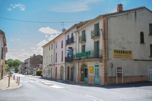 A street view with buildings, including a pharmacy with a sign that reads 'PHARMACIE' and 'MATERIEL MEDICAL Location - Vente'.