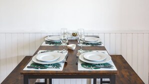 A dining table set with plates, glasses, and cutlery, featuring a tropical leaf pattern on the placemats. - Cosy Apartment in Ancient Gabian with River and Vineyard Views (Gabian)