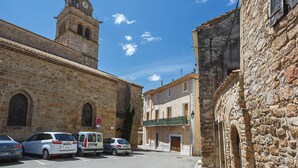 A historic stone building with a clock tower, parked cars, and a clear blue sky. - Cosy Apartment in Ancient Gabian with River and Vineyard Views (Gabian)