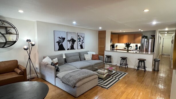 A modern living room with a grey sofa, a coffee table, and a dining table.