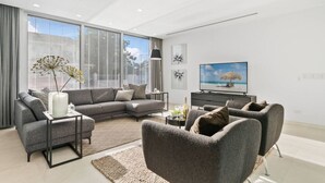 A modern living room with a grey sectional sofa, a coffee table, and a TV on a black stand.