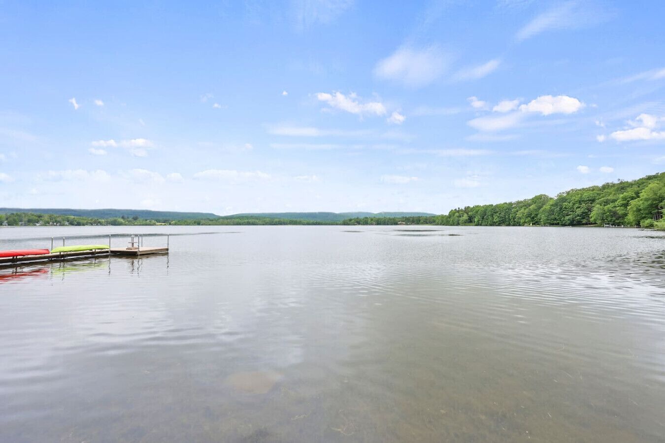 Un lago tranquilo con un muelle y canoas.