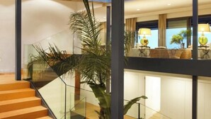 A modern interior with a glass staircase, wooden flooring, and a view of the living area.