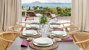 A dining table set for six with a view of the sea and mountains.
