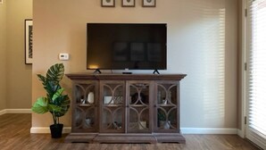 A living room with a flat-screen TV on a wooden cabinet, a potted plant, and framed pictures on the wall. - Executive 1st Floor 2BR Dublin Area W D Gym (Dublin)