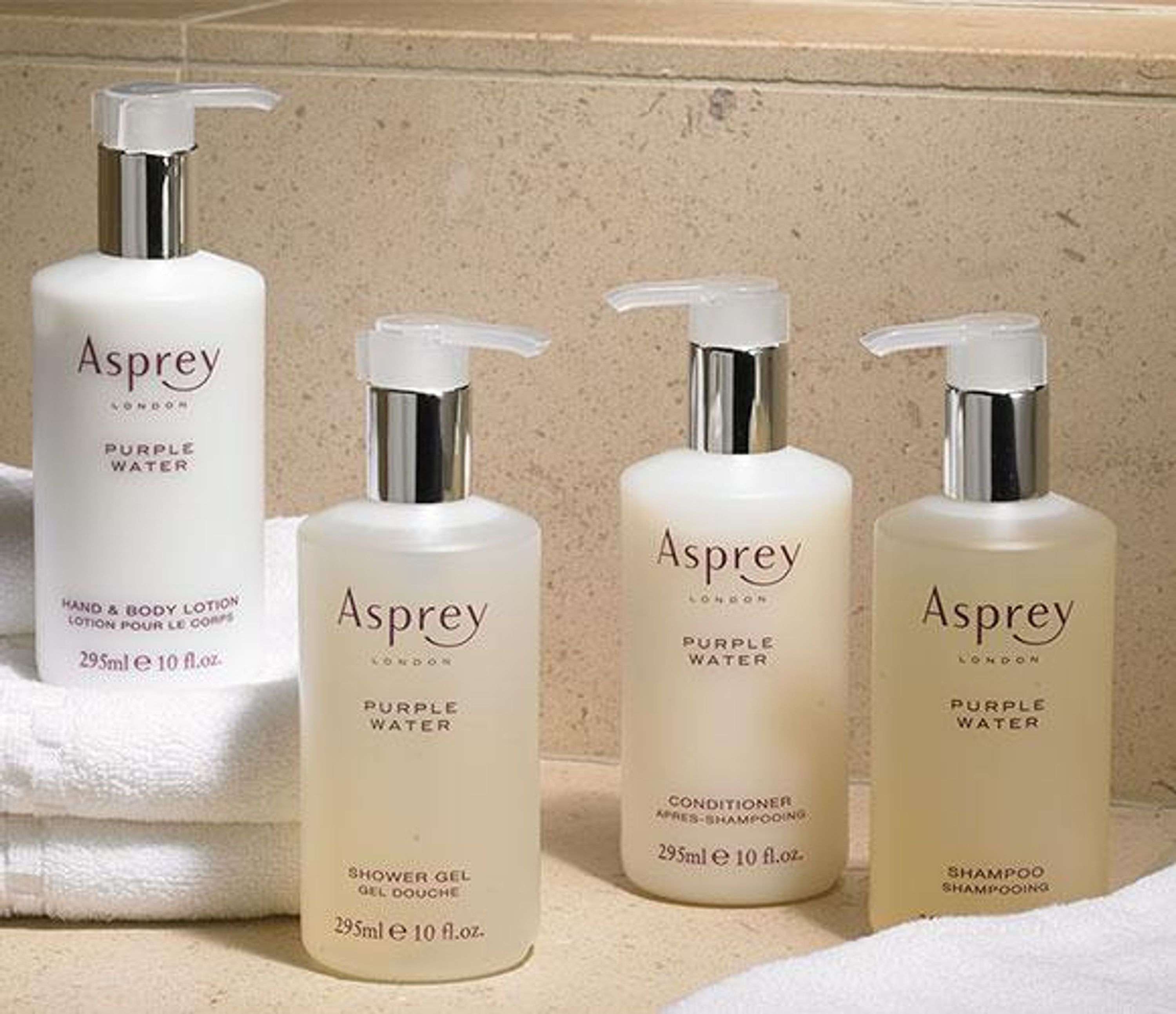 Cuatro botellas de productos Asprey Purple Water sobre una encimera.