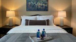 A hotel room with a large bed, two bedside tables with lamps, a painting on the wall, and a tray with water bottles and a figurine. - Executive 1st Floor 2BR Dublin Area W D Gym (Dublin)