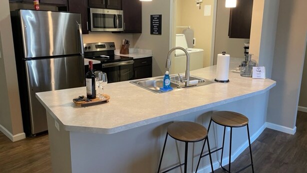 A modern kitchen with stainless steel appliances, a central island with stools, and pendant lighting. - Executive 1st Floor 2BR Dublin Area W D Gym (Dublin)