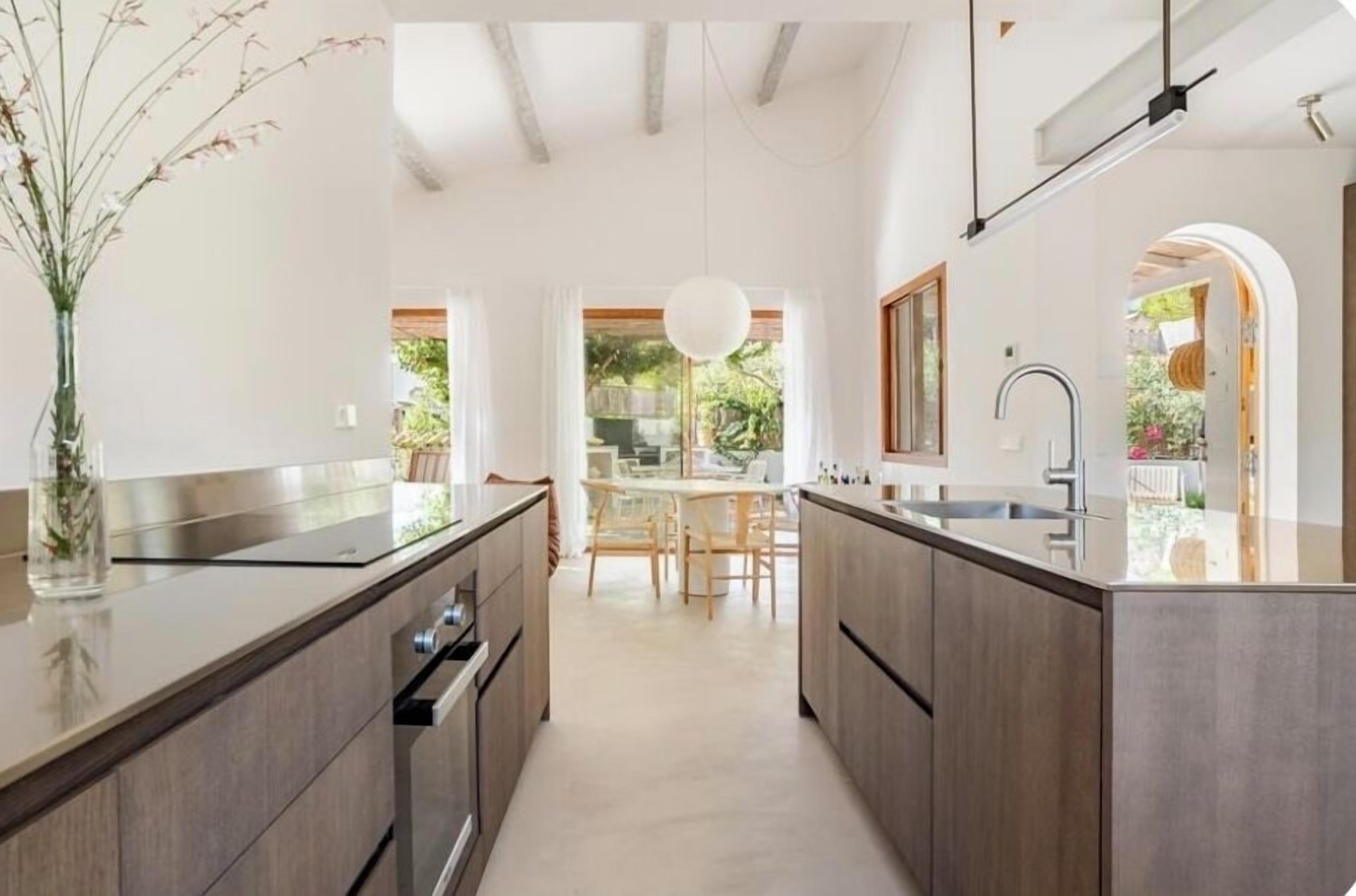 A modern kitchen with a central island, wooden cabinets, and a view into a dining area.