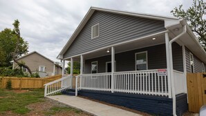 A two-story house with a covered porch and a wooden fence.