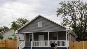 A two-story house with a front porch, a mailbox, and a fire hydrant in the yard.
