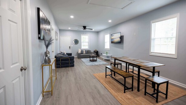 A spacious living area with a dining table, sofas, and a ceiling fan.
