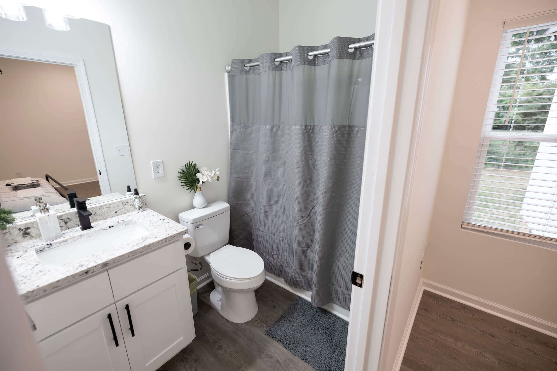 Ein Badezimmer mit Toilette, einem Waschbecken mit Marmorplatte und einer Duschvorhang.