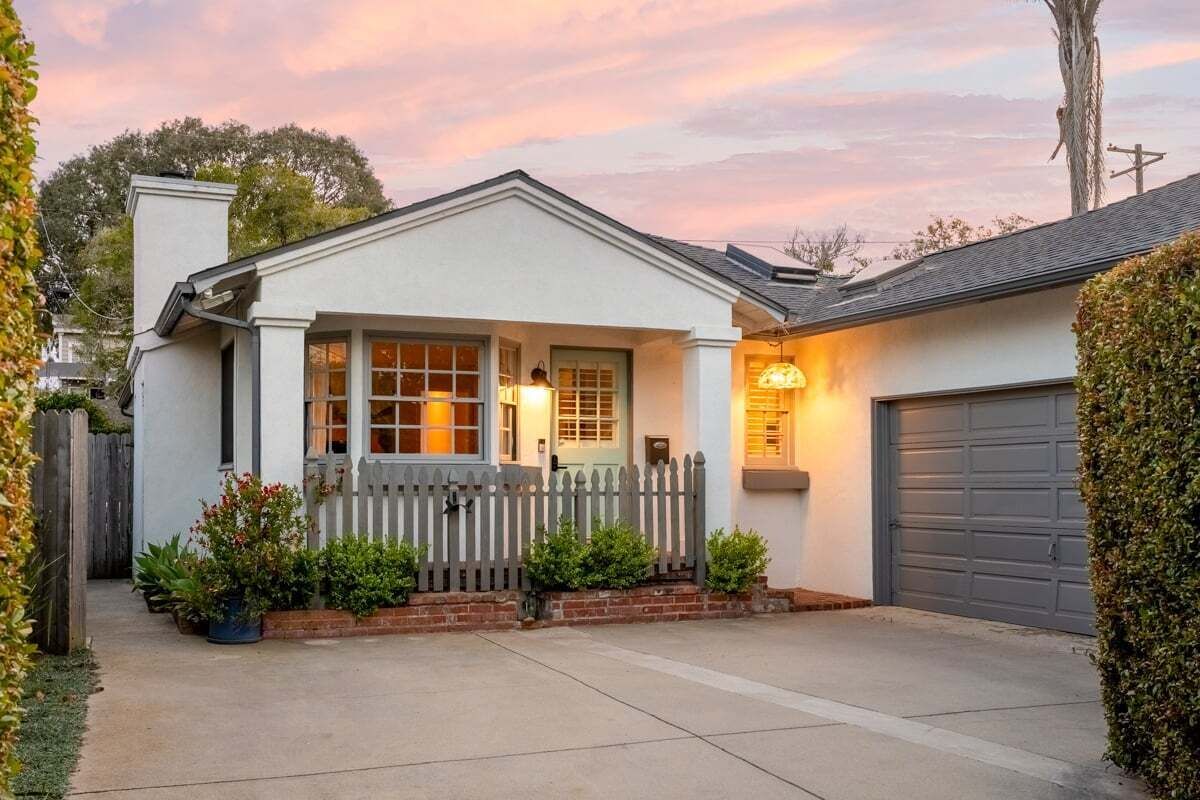A single-story house with a front porch, a garage, and a picket fence.